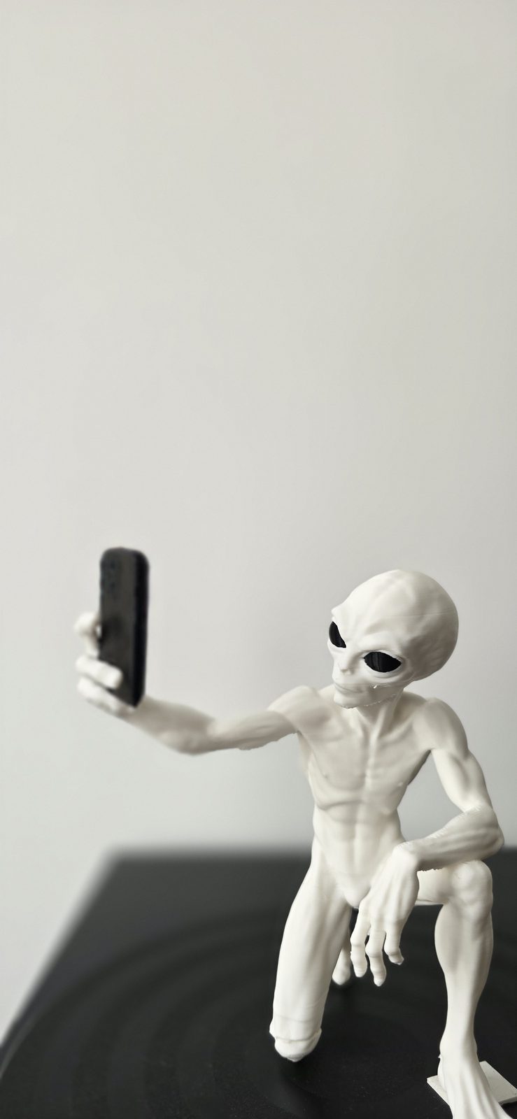 Weiß gedruckte Alien-Figur, die ein Selfie mit einem Smartphone macht